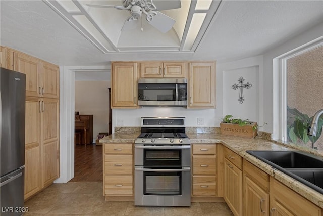 kitchen featuring light brown cabinetry, sink, light tile patterned floors, and stainless steel appliances