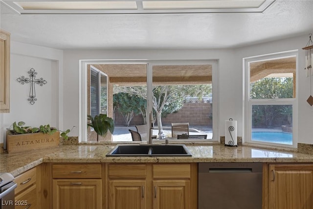 kitchen with light stone counters, range, dishwasher, and sink