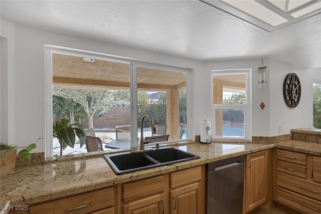 kitchen featuring a healthy amount of sunlight, sink, a textured ceiling, and dishwasher