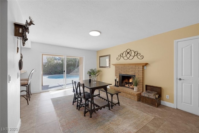 dining area featuring a textured ceiling, a brick fireplace, and light tile patterned floors