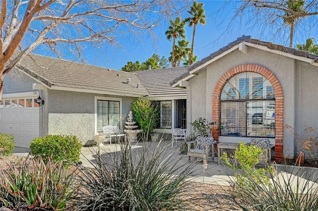 view of front of home featuring a tile roof, an attached garage, and stucco siding