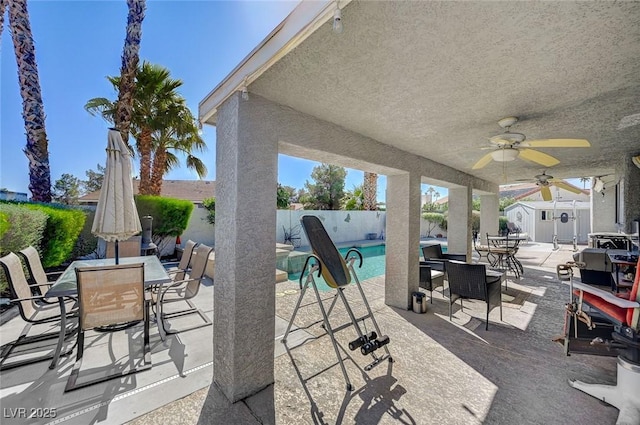 view of patio / terrace with a storage unit, outdoor dining space, a fenced backyard, and a ceiling fan