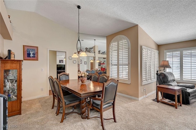 dining space featuring lofted ceiling, light colored carpet, and baseboards