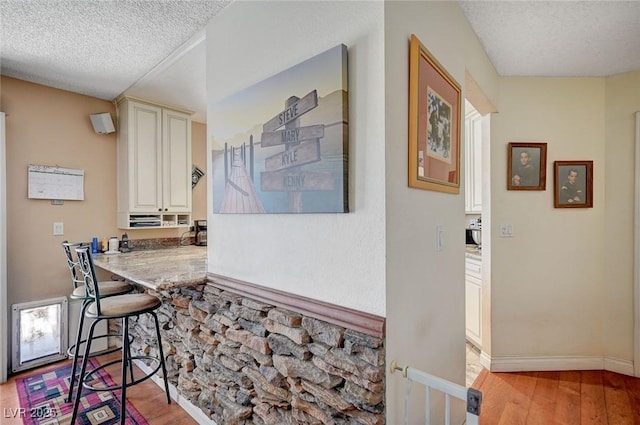 dining space featuring a textured ceiling, light wood-style flooring, and baseboards