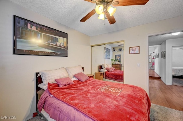 bedroom featuring a textured ceiling, a closet, wood finished floors, and a ceiling fan