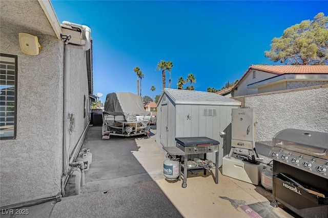 view of patio / terrace featuring a grill, fence, a storage unit, and an outbuilding