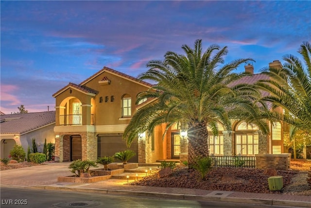 mediterranean / spanish-style home featuring a garage and a balcony