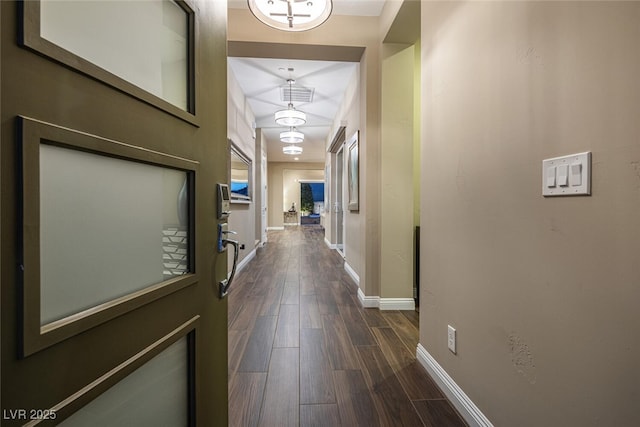 hallway featuring dark wood-type flooring, visible vents, and baseboards