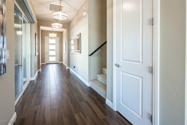 doorway with stairway, baseboards, visible vents, and dark wood-style flooring