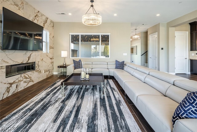 living area featuring recessed lighting, visible vents, a high end fireplace, wood finished floors, and a chandelier