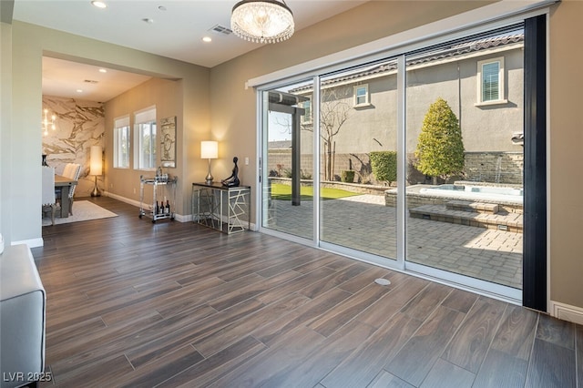 doorway with baseboards, visible vents, wood finished floors, and recessed lighting