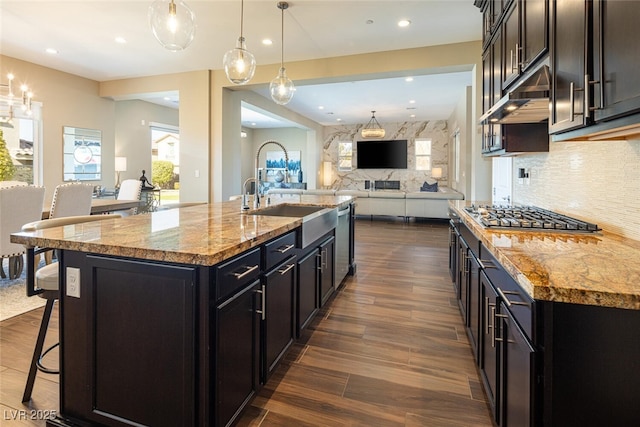 kitchen with dark wood finished floors, appliances with stainless steel finishes, open floor plan, a sink, and a kitchen breakfast bar