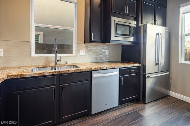 kitchen with dark cabinets, tasteful backsplash, appliances with stainless steel finishes, and a sink