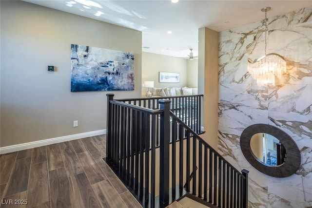 interior space with baseboards, wood finished floors, an inviting chandelier, an upstairs landing, and recessed lighting