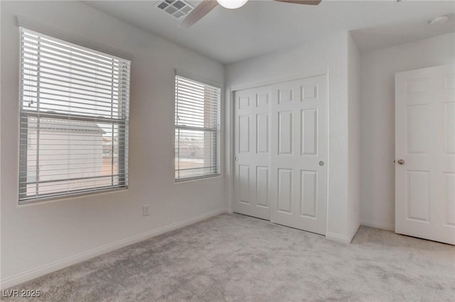 unfurnished bedroom featuring light colored carpet, a closet, and ceiling fan