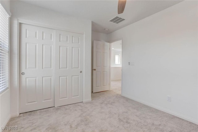 unfurnished bedroom featuring ceiling fan, a closet, and light carpet