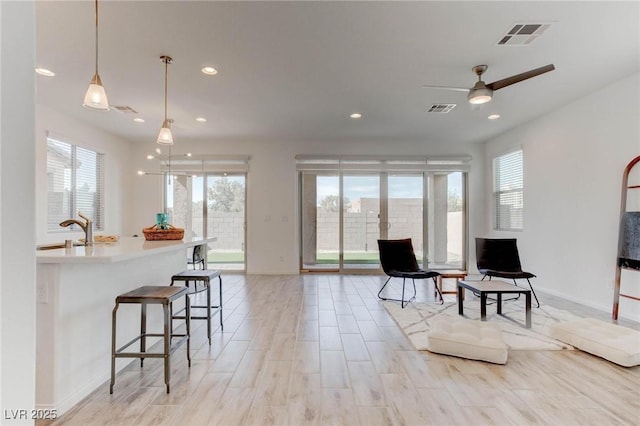 living area featuring sink, light hardwood / wood-style floors, and ceiling fan