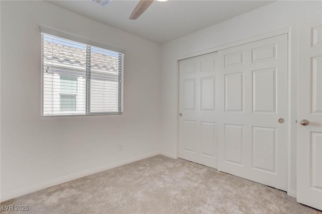 unfurnished bedroom featuring light colored carpet, a closet, and ceiling fan