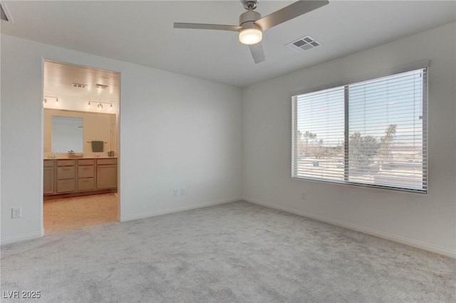 unfurnished bedroom with ceiling fan, light carpet, and ensuite bath