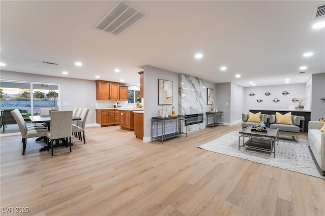 living area featuring light wood finished floors, baseboards, visible vents, and recessed lighting