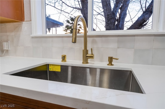 room details featuring tasteful backsplash, light countertops, and a sink