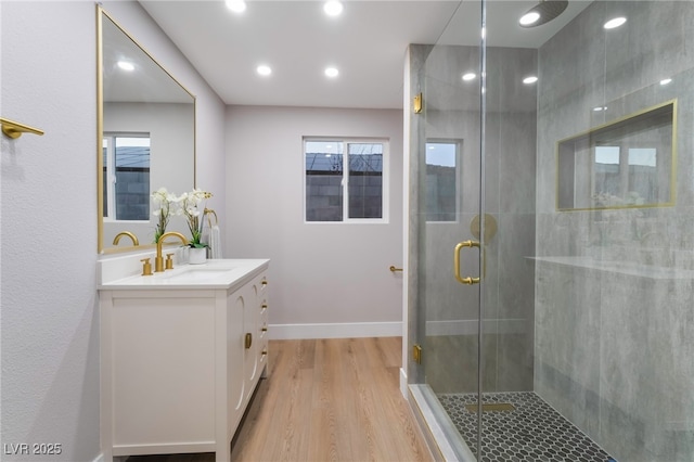 bathroom with a stall shower, baseboards, wood finished floors, vanity, and recessed lighting