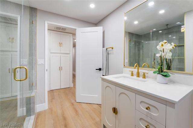 bathroom featuring recessed lighting, visible vents, vanity, a shower stall, and wood finished floors