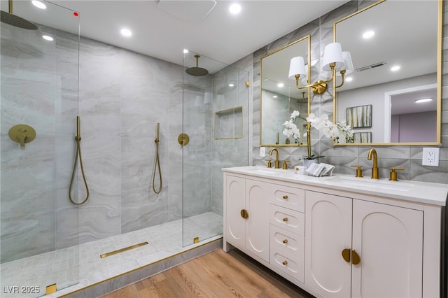 full bathroom featuring visible vents, a walk in shower, a sink, and wood finished floors