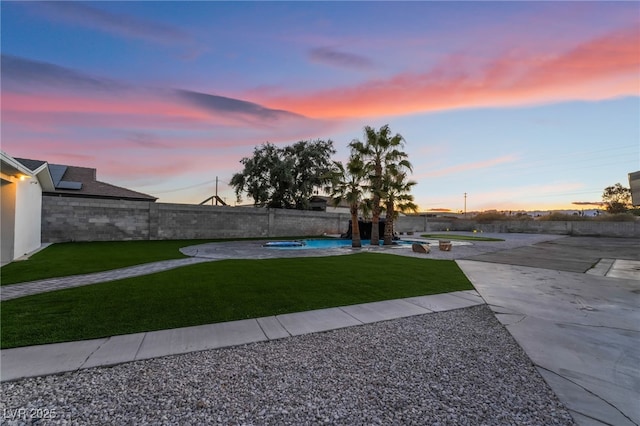 yard at dusk with an in ground hot tub, a patio area, a fenced backyard, and a fenced in pool