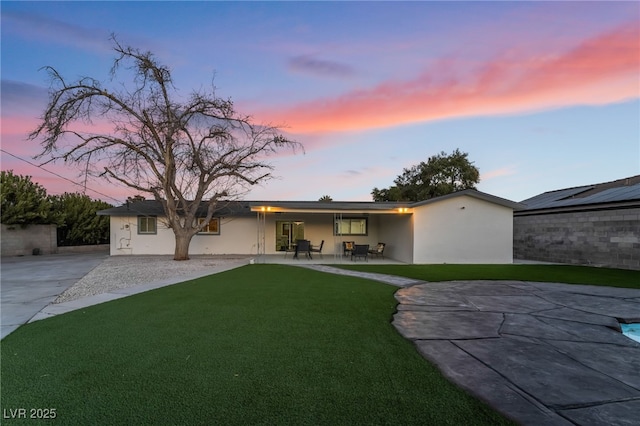 view of front facade featuring a front yard, concrete driveway, a patio area, and stucco siding