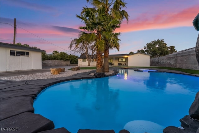 pool at dusk with a patio area, fence, and a fenced in pool