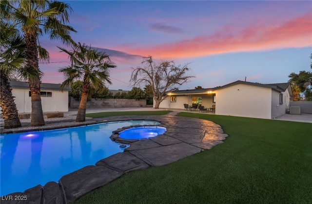 pool at dusk featuring an outdoor pool, a patio area, a lawn, and fence