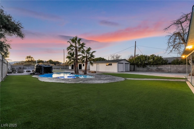view of yard featuring a garage, an outdoor pool, a fenced backyard, and an outdoor structure