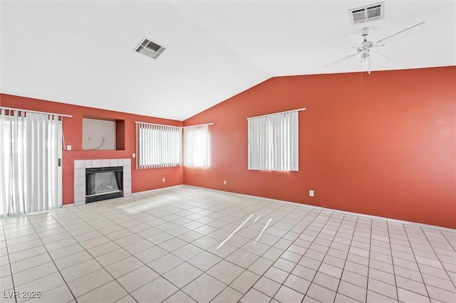 unfurnished living room featuring ceiling fan, lofted ceiling, a tiled fireplace, and light tile patterned floors