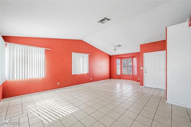 empty room featuring lofted ceiling, light tile patterned floors, and ceiling fan