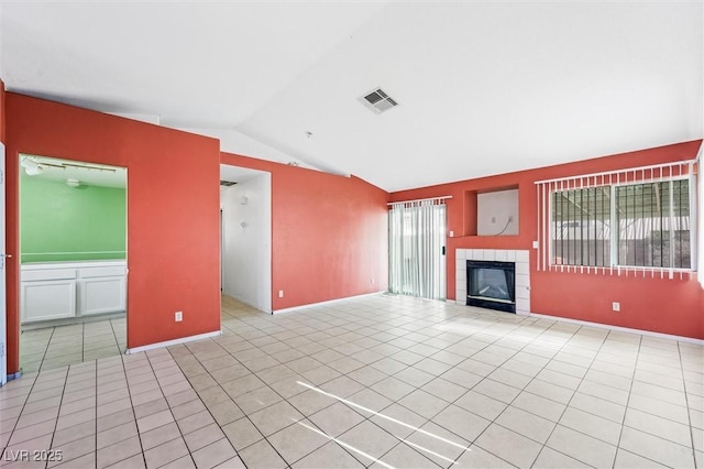 unfurnished living room featuring a healthy amount of sunlight, lofted ceiling, a fireplace, and light tile patterned floors