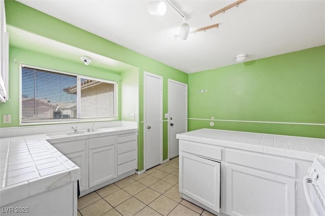 kitchen with rail lighting, white cabinets, tile counters, range, and light tile patterned floors