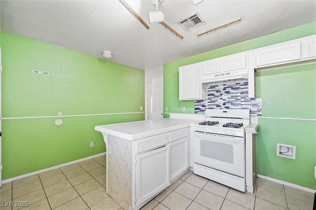 kitchen with tasteful backsplash, white gas stove, white cabinets, and kitchen peninsula