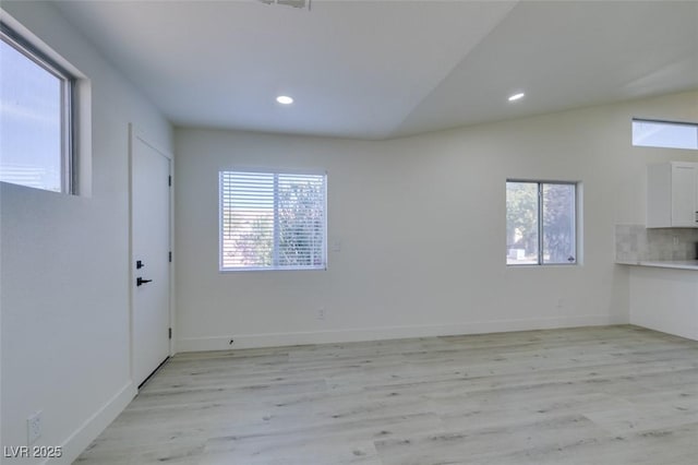 spare room with lofted ceiling and light hardwood / wood-style flooring