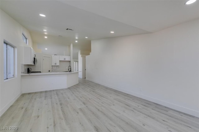 unfurnished living room with sink and light wood-type flooring