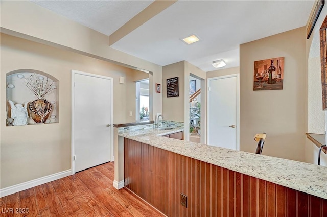 kitchen featuring sink, light stone countertops, and light hardwood / wood-style floors