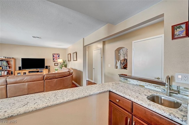 kitchen featuring light stone countertops, sink, and a textured ceiling