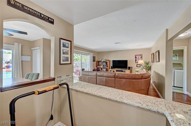 living room with ceiling fan, wood-type flooring, washer / clothes dryer, and a textured ceiling