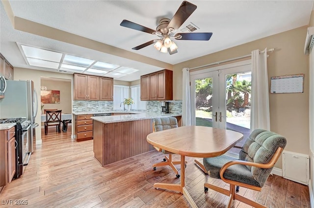 kitchen featuring french doors, gas range, backsplash, and light hardwood / wood-style flooring