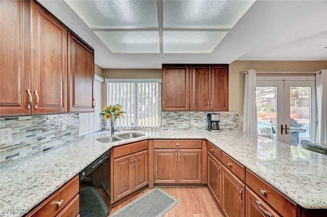 kitchen featuring black dishwasher, backsplash, kitchen peninsula, light stone countertops, and light wood-type flooring