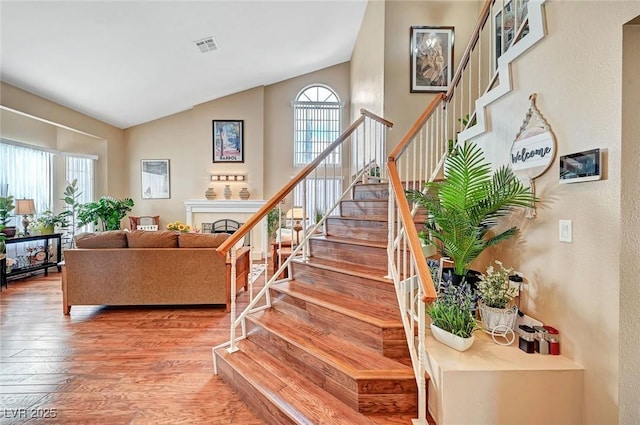 staircase featuring high vaulted ceiling and hardwood / wood-style floors