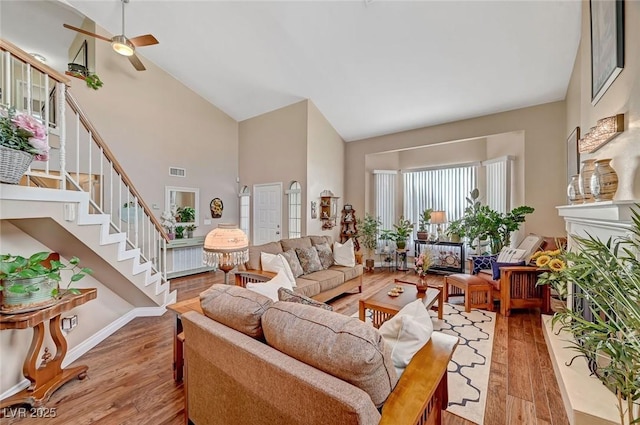 living room with ceiling fan, high vaulted ceiling, and light wood-type flooring