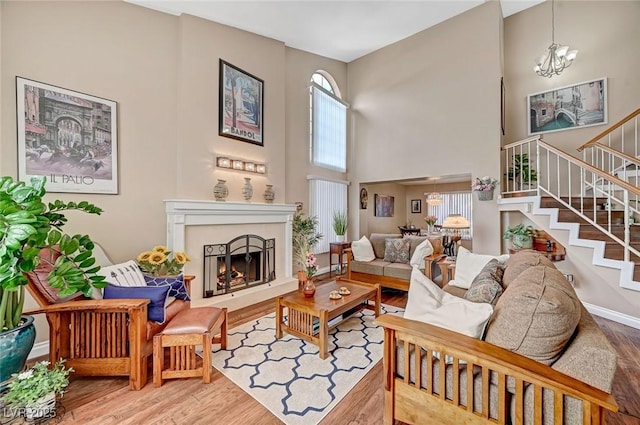 living room with a high ceiling, wood-type flooring, and a notable chandelier