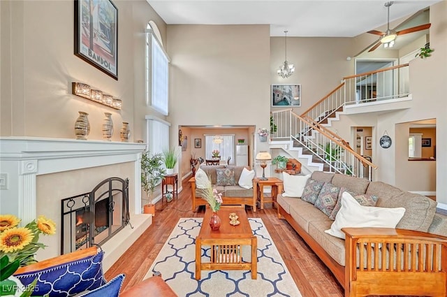 living room featuring a towering ceiling, a notable chandelier, and light hardwood / wood-style flooring