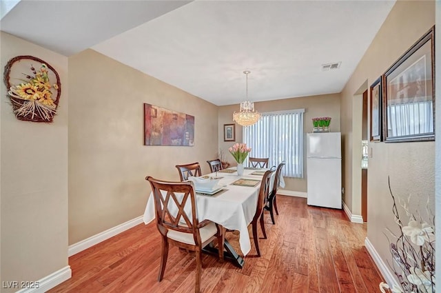 dining area with a notable chandelier and light hardwood / wood-style flooring